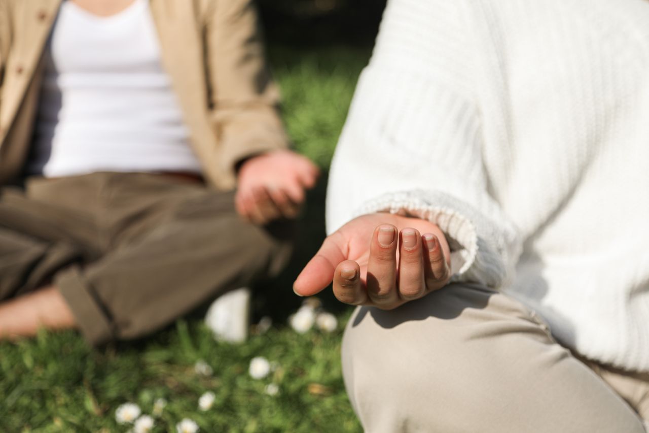 services-05 Two people meditating outdoors, focusing on hands in a peaceful setting.